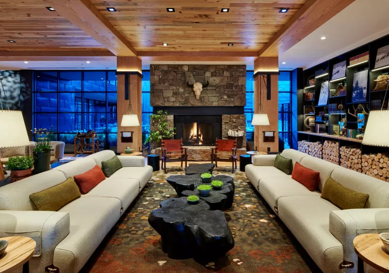 Lobby hotel with couches, black wood coffee tables and a stone fireplace