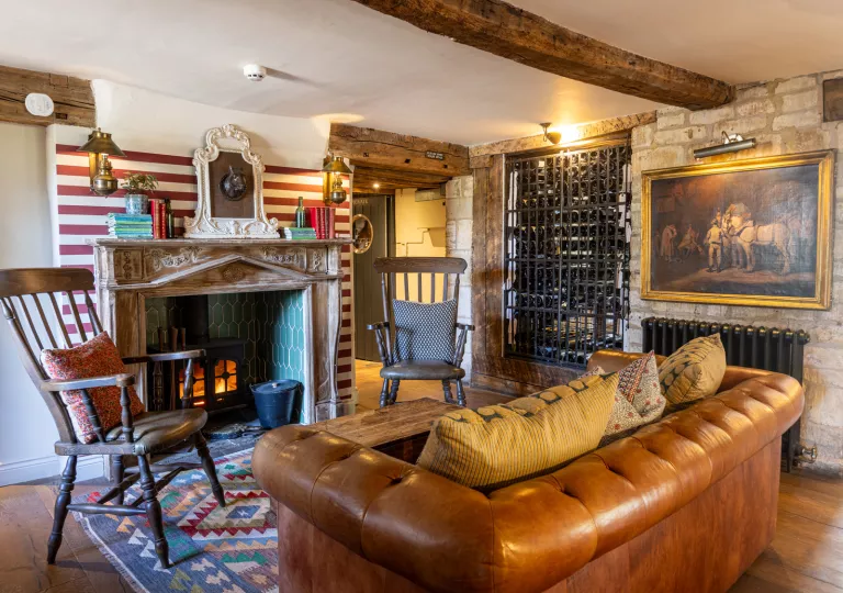 Living room and lounge with cushioned, leather couches in front of a fireplace