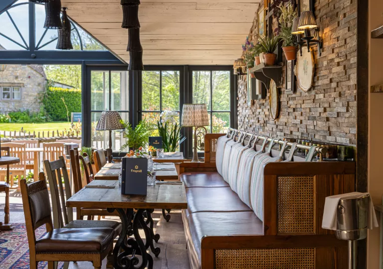 Restaurant dining hall with cushioned sofas and chairs surrounding square dining tables