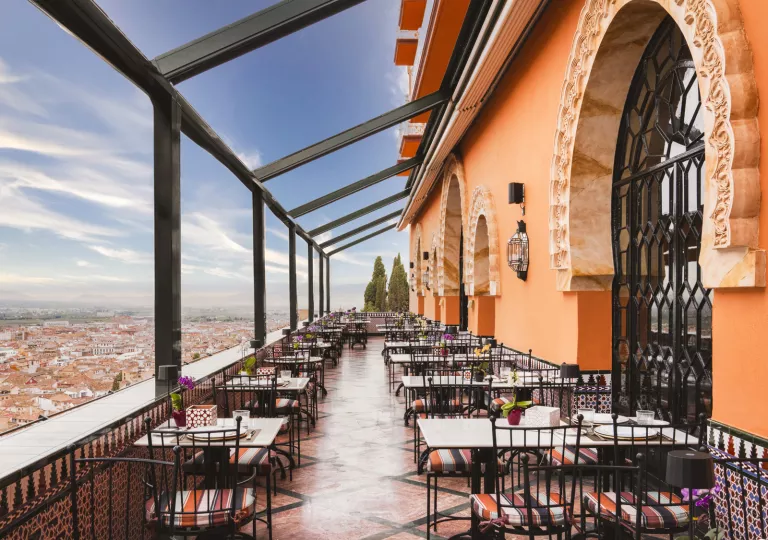 Outdoor patio with tables and chairs, looking out towards a town