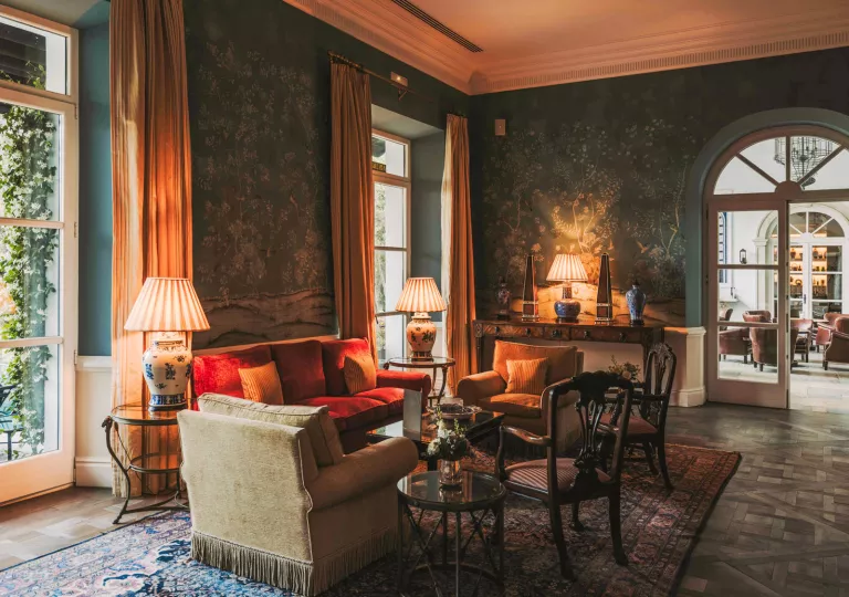 Seating area with cushioned sofas and chairs, with warm lamps around the room