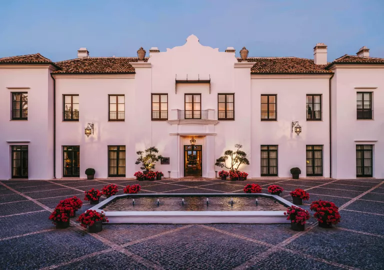 Exterior, outdoor view of large white building with a fountain in front