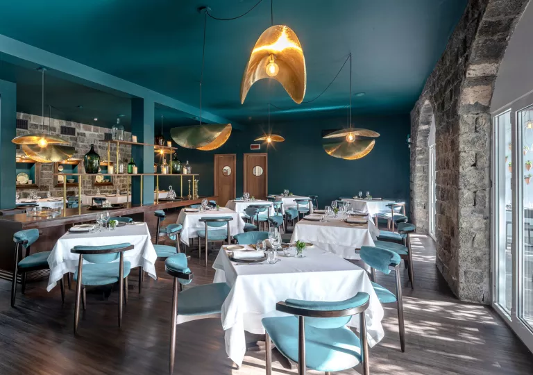Dining hall with square, white tables and teal chairs