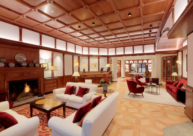 Hotel lobb with wooden ceilings and white walls, with white sofas and red pillows