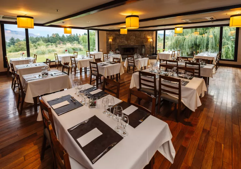 Indoor dining hall with square, white tables and large windows