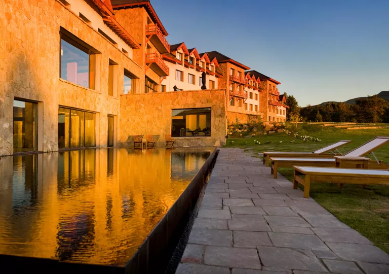 Exterior view of hotel building with an outdoor pool, and large grass area