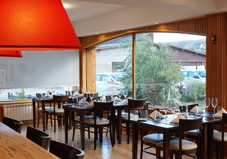 Restaurant dining room with wooden tables and chairs, with large windows to the right