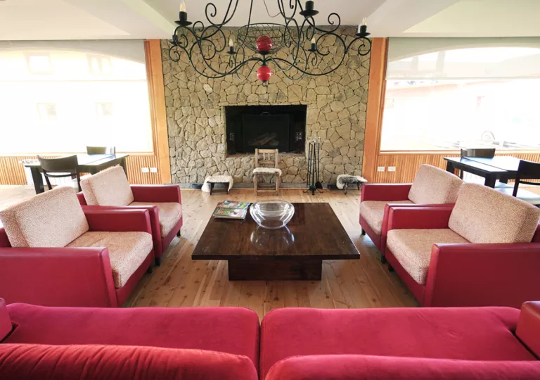 Lounge with red cushioned chairs and a stone wall in the back