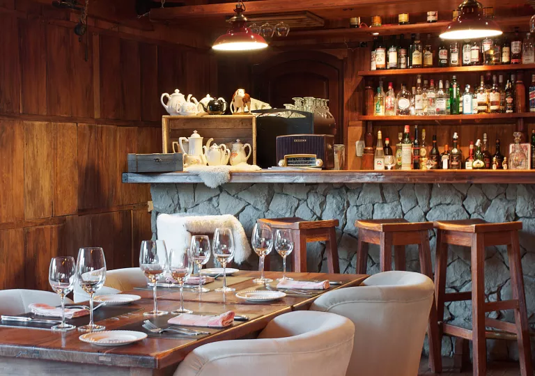 Bar and lounge with a dining table and wine glasses in front