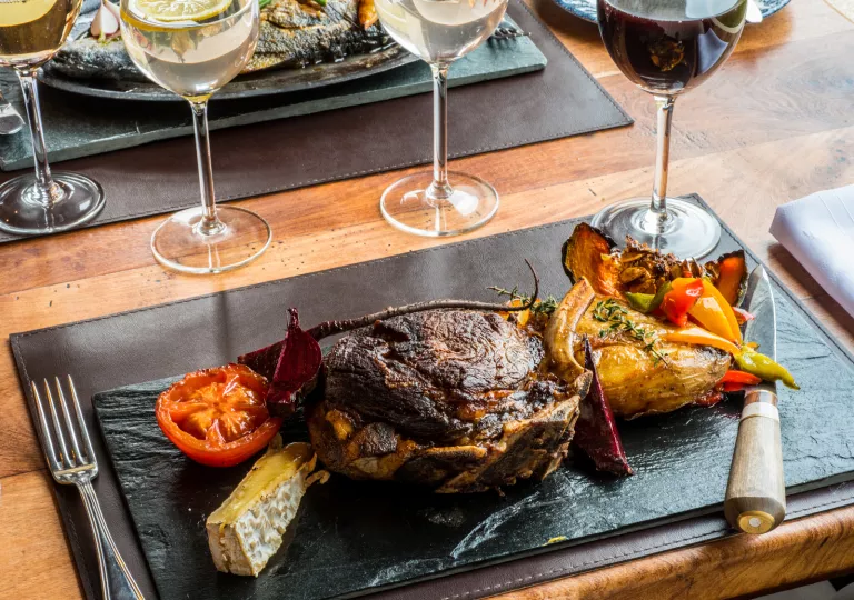 Black plate with roasted meat and vegetables