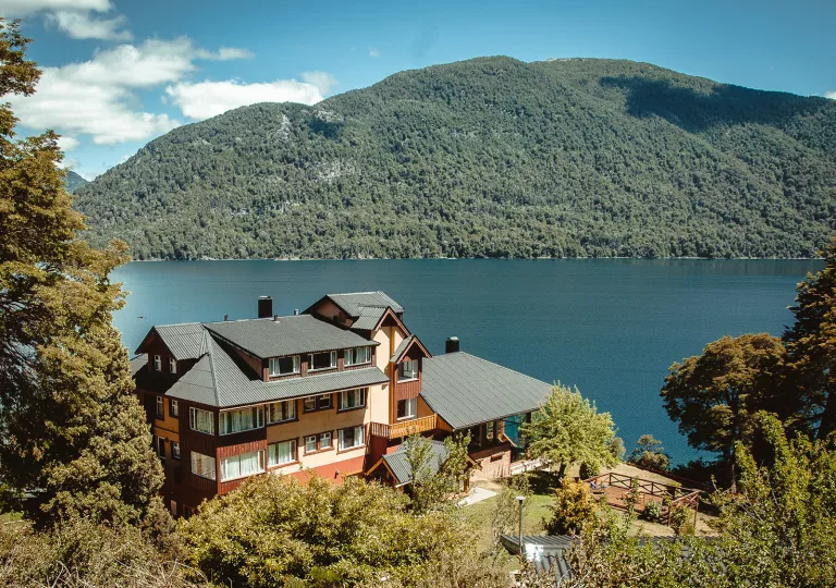 Exterior view of multi-level building with a hills in the background and a lake