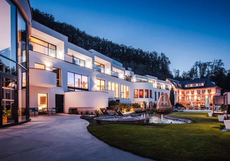 Exterior view of long, white hotel building with illuminated rooms