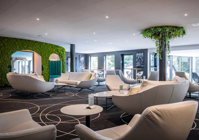 Room with large, cushioned sofas and large pillars covered in leaves