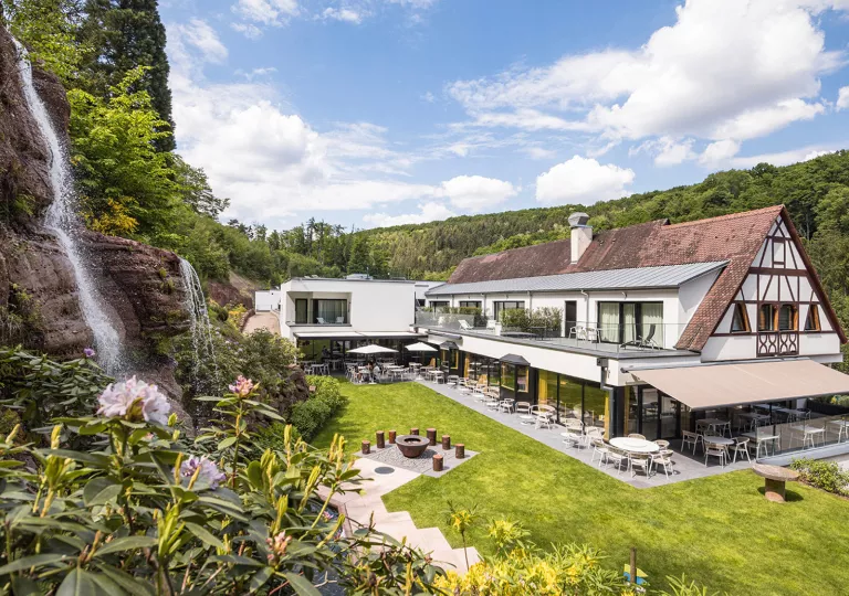 Exterior view of hotel building with an outdoor patio and a small waterfall
