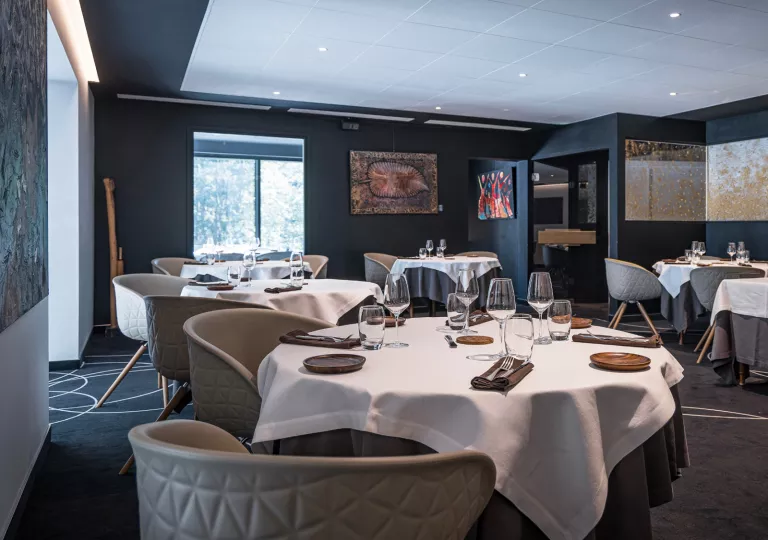 Restaurant dining room with multiple, circular tables and wine glasses on each table