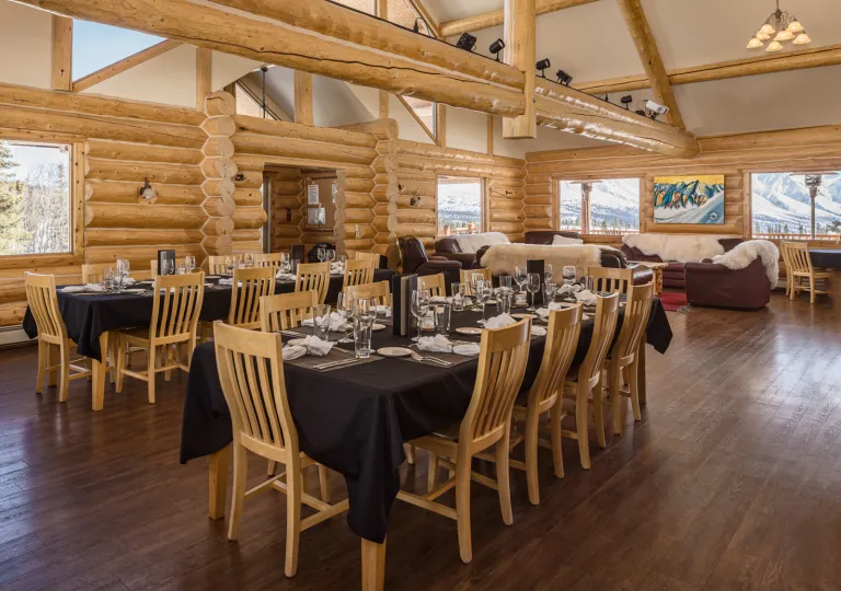 Dining hall in a cabin, with wooden chairs around black dining tables