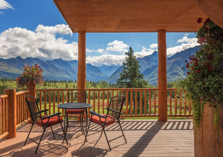Outdoor patio with metal chairs and tables, with views of a forest