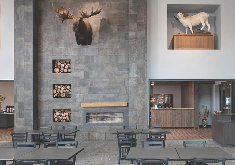 Restaurant dining hall with large stone walls and black dining tables