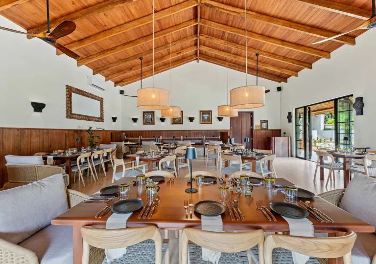 Restaurant dining hall with wooden tables and cushioned chairs, and circular light fixtures