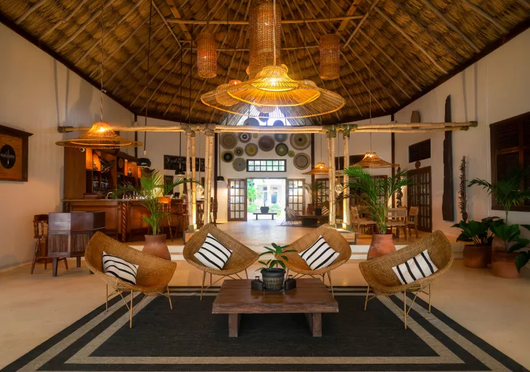 Large bar and lounge with straw chairs and a wooden table in the center