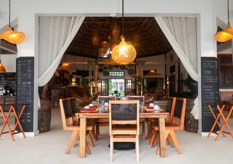 Dining table with wooden chairs in a restaurant, with a large entryway with curtains