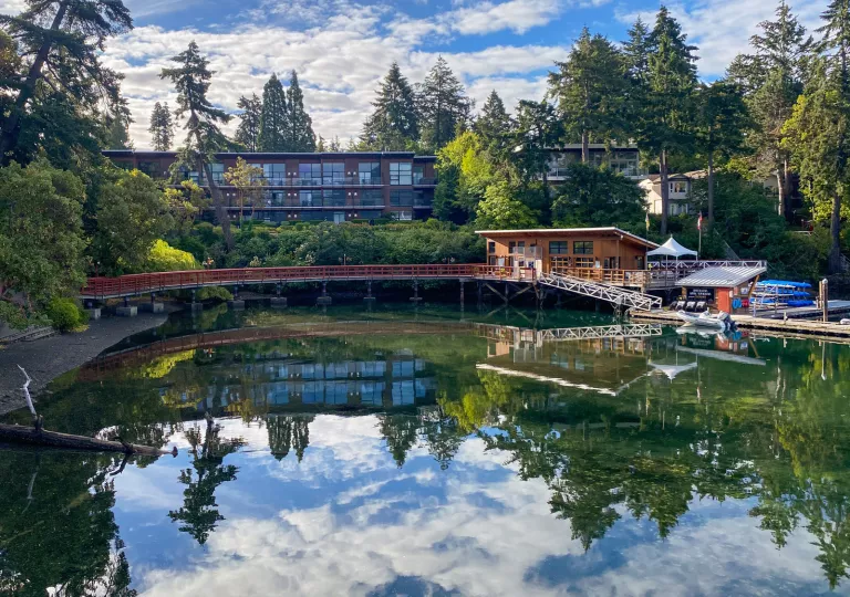 Exterior view of large hotel building with a lake and wooden bridge in front