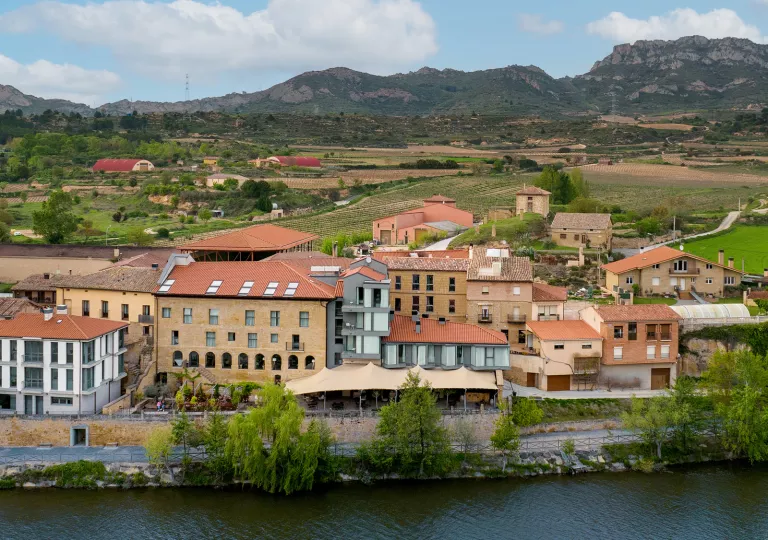 Exterior, sky view of a red and orange hotel complex, with crop fields in the distance