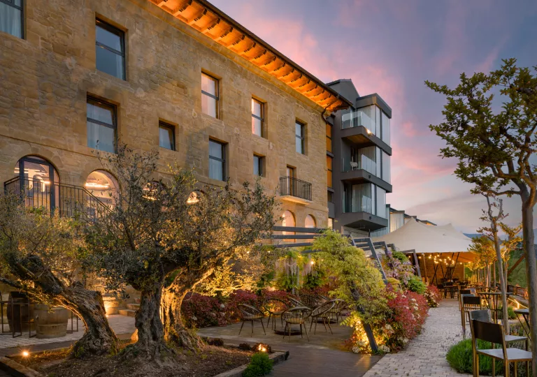 Exterior view of brick, multi-story building with a garden patio in front