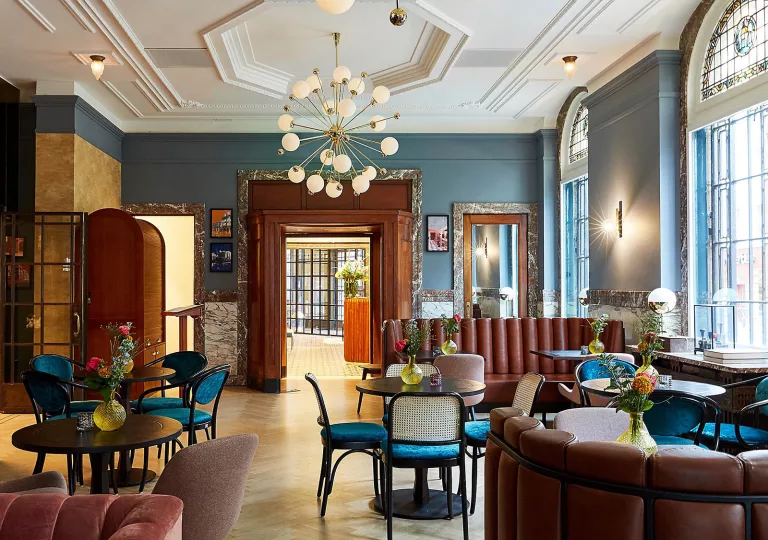 Hotel lounge and seating area with cushioned sofas and chairs, in front of circular tables