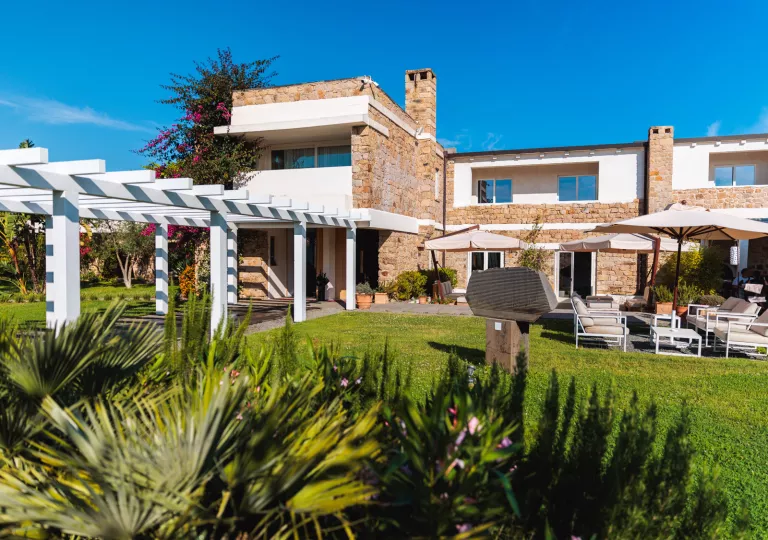 Exterior view of stone and white building with a garden and grass area in front