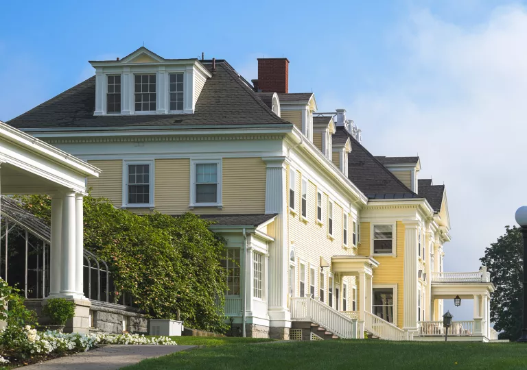 Exterior view of large, yellow building with a large grass field in front