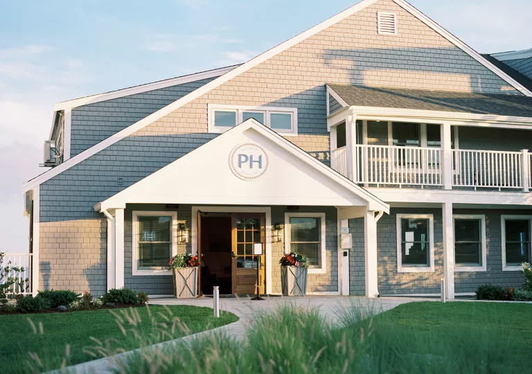 Exterior view of white and gray hotel building with a grass field in front