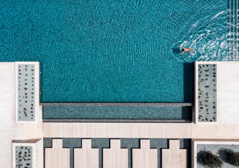 Top-down view of an outdoor pool with a person swimming in the pool