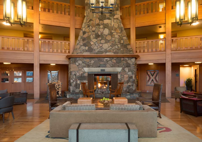 Hotel lobby with large light fixtures and a stone fireplace in the center