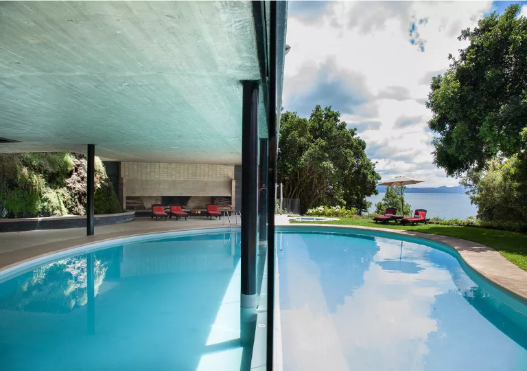 Outdoor pool with a large building covering and a lake in the background