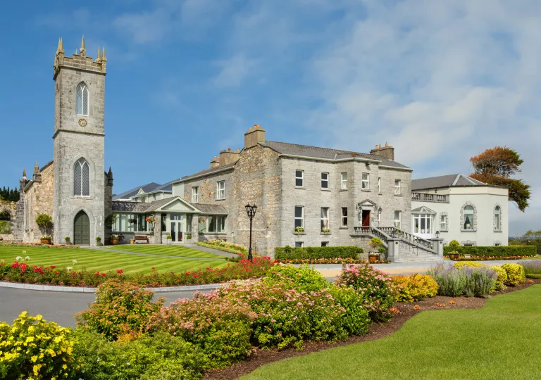 Exterior view of stone building with trimmed grass fields and flower beds