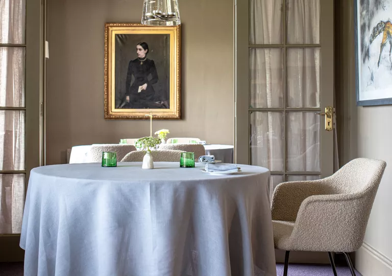 Circular dining table with gray cloth, and paintings on the wall
