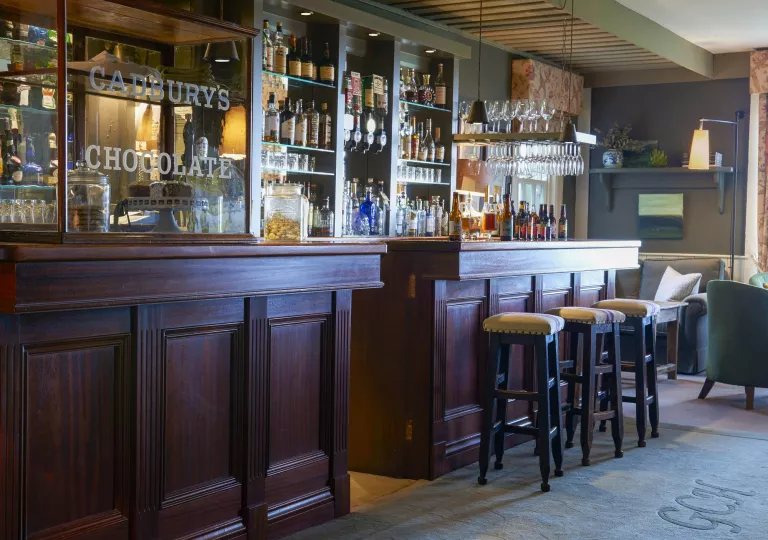 Indoor bar with redwood counters and cushioned stools, with alcohol bottles along the walls