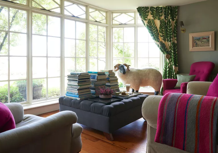 Indoor library with large, cushioned sofas and stacks of books on an ottoman