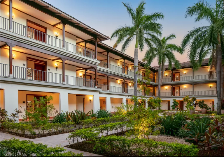 Hotel buildings with 3 stories with balconies and a garden in the center