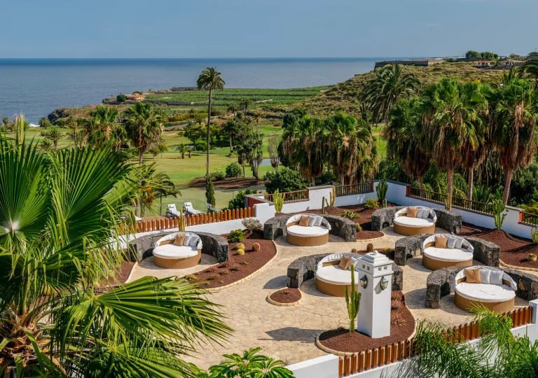 Outdoor patio with circular, white and brown chairs, looking out towards the ocean