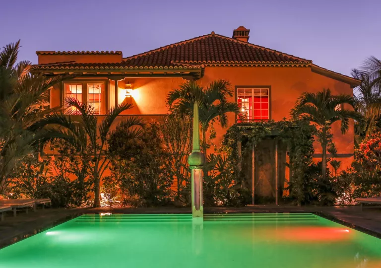 Nighttime exterior view of a pink building and an outdoor pool