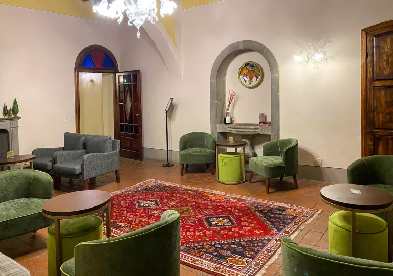 Room with a patterned, red rug on the floor and green chairs around the room