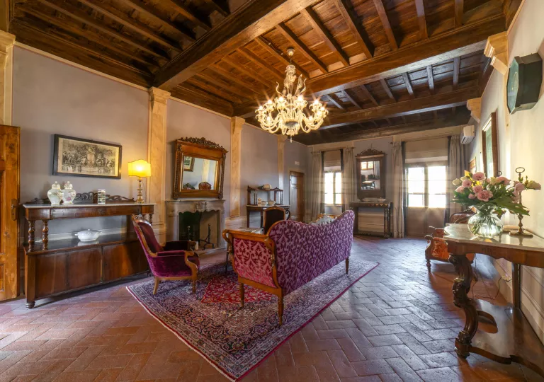 Room with tile flooring and red velvet chairs, and furniture along the walls