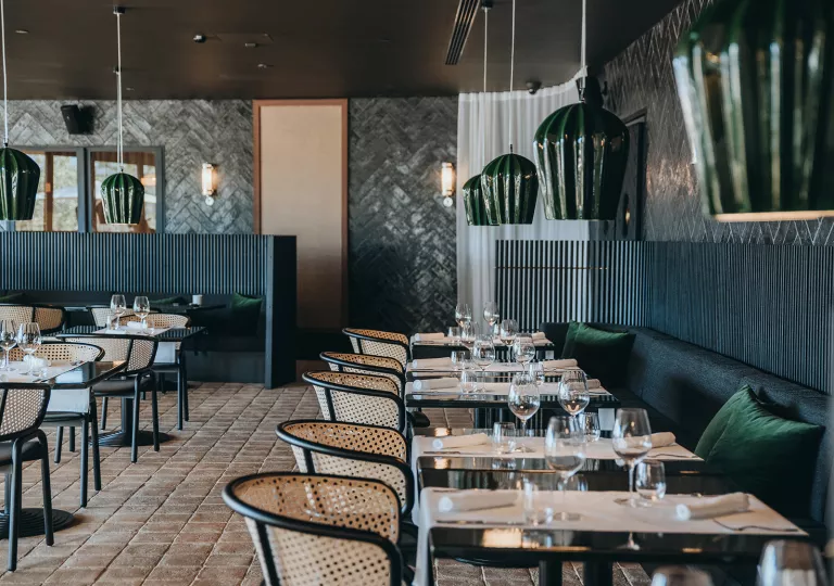 Indoor dining hall with woven chairs and green sofas