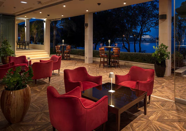 Outdoor hotel patio with red, cushioned chairs and square tables