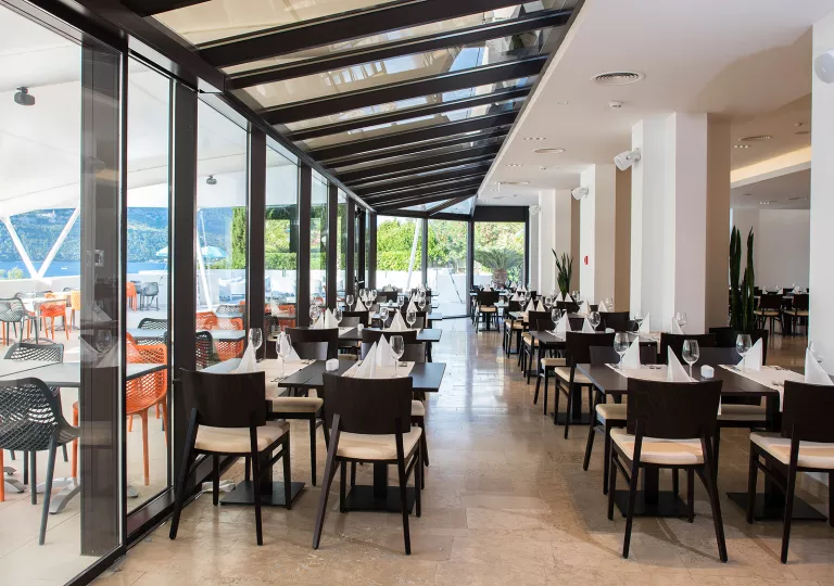 Indoor dining hall with black furniture and glass walls looking out to the ocean