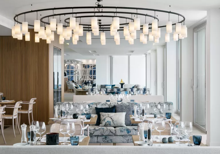 Large dining room with multiple square tables and wine glasses on each table