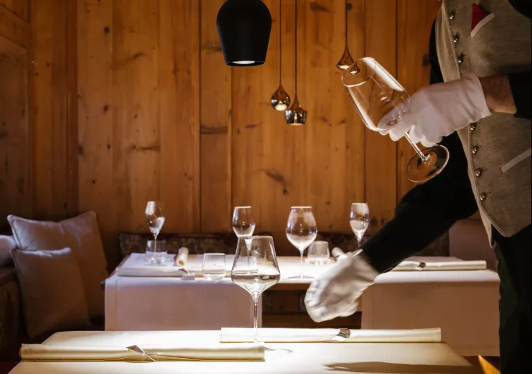 Waiter putting wine glasses on a dining table