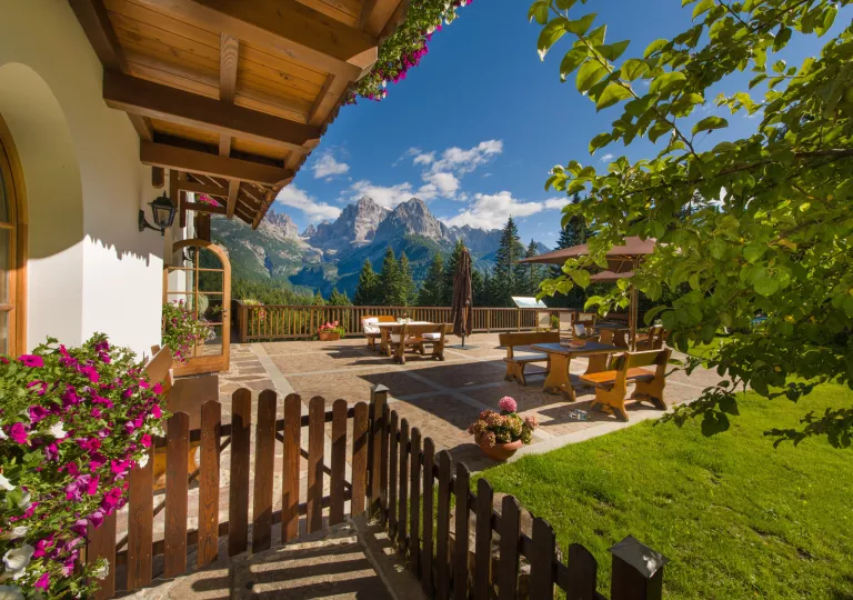 Outdoor patio with wooden tables and benches, with large mountains in the distance